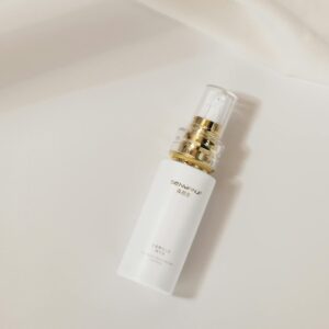 Elegant white skincare bottle with gold accents lying on a soft cream background, suggesting luxury and sophistication.
