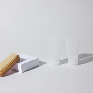 Simple arrangement of a brush and tubes on a white background with shadows.