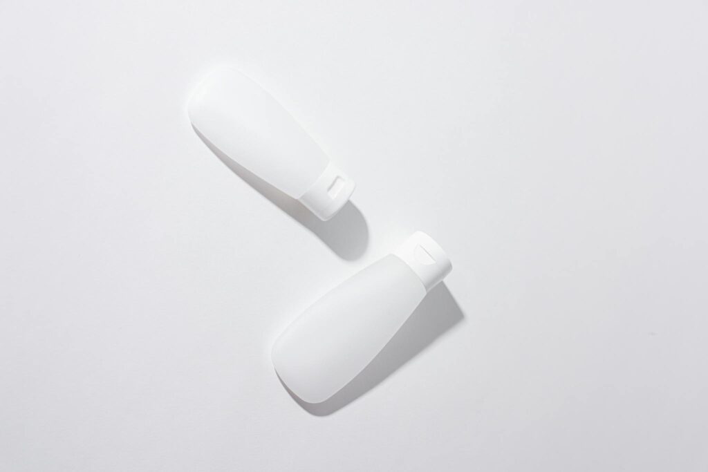 Two white cosmetic containers in a minimalist flat lay composition on a neutral background.
