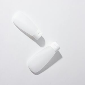 Two white cosmetic containers in a minimalist flat lay composition on a neutral background.
